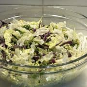 A close-up side view of a vibrant salad in a large glass bowl.